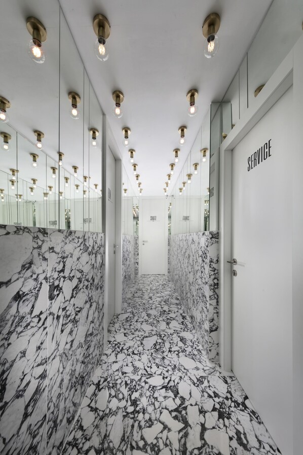 A modern hallway with marble flooring and mirrored walls, leading to a service area. - Bezalel Suites (Jerusalem)