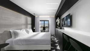 Habitación de hotel moderna con una cama grande, un escritorio y vistas a la ciudad a través del ventanal.