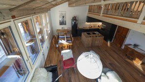 A spacious loft with a high ceiling, wooden beams, a dining area with a table and chairs, a kitchen with a bar, and large windows offering views. - Cozy apartment with high comfort for max. 6 people TIP bookable from 27.12.2025  (Schmitten)