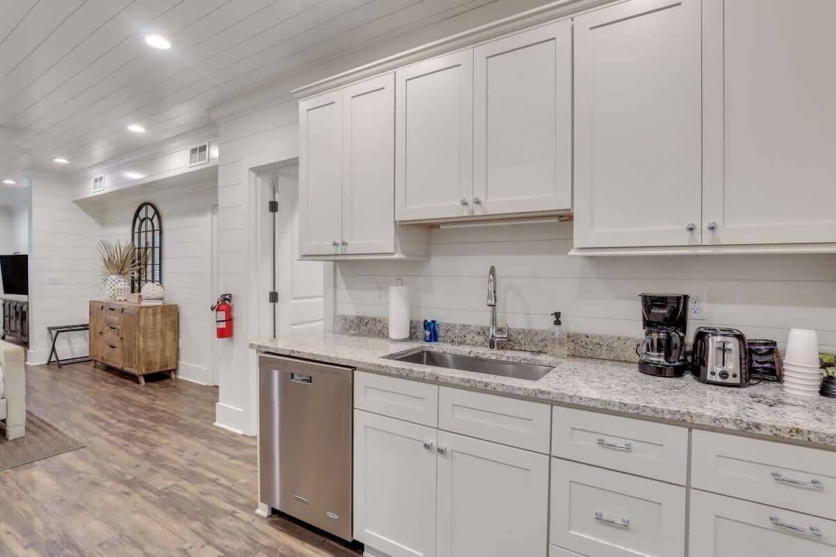 A modern kitchen with white cabinets, a granite countertop, and stainless steel appliances.