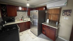 A kitchen with dark wooden cabinets, a stainless steel refrigerator, a microwave, and a coffee maker. - This property is located in a quiet family oriented gated community in Portmore. (Portmore)
