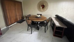 A dining area with a round table, chairs, a chandelier, a mirror, and a sofa. - This property is located in a quiet family oriented gated community in Portmore. (Portmore)
