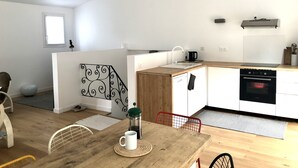 A modern kitchen with a wooden countertop, white cabinets, and a built-in oven. There is a dining table with chairs and a coffee maker on the table. - Renovated house, Collioure near center, mountain views, quiet (Collioure)