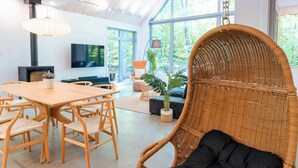 A modern interior with a dining area, hanging chair, and large windows. - Bright Cottage - 3 min from Tremblant North Slope (Lac-Supérieur)