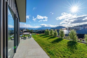 A modern building with a glass facade, outdoor seating, and a view of mountains.