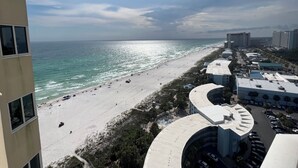 Une vue sur la plage, avec une plage de sable blanc, l’océan et des bâtiments en arrière-plan.