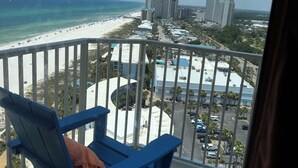 Un balcon avec vue sur une plage, un parking et des immeubles.