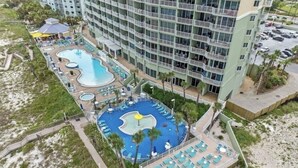Un hôtel doté de plusieurs piscines, d’une plage et d’un grand bâtiment avec des balcons.