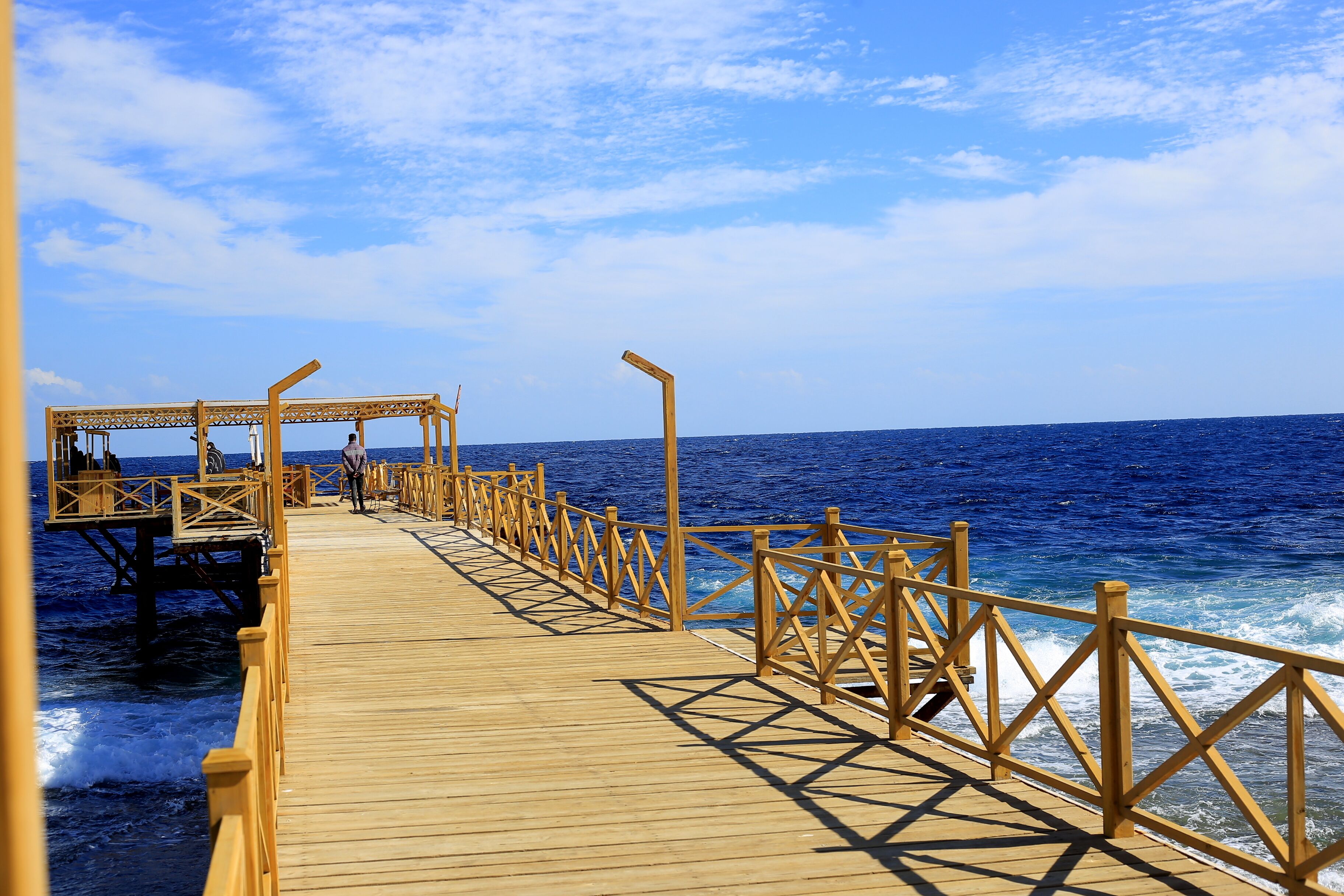 A wooden pier extending into the ocean with a wooden structure at the end.