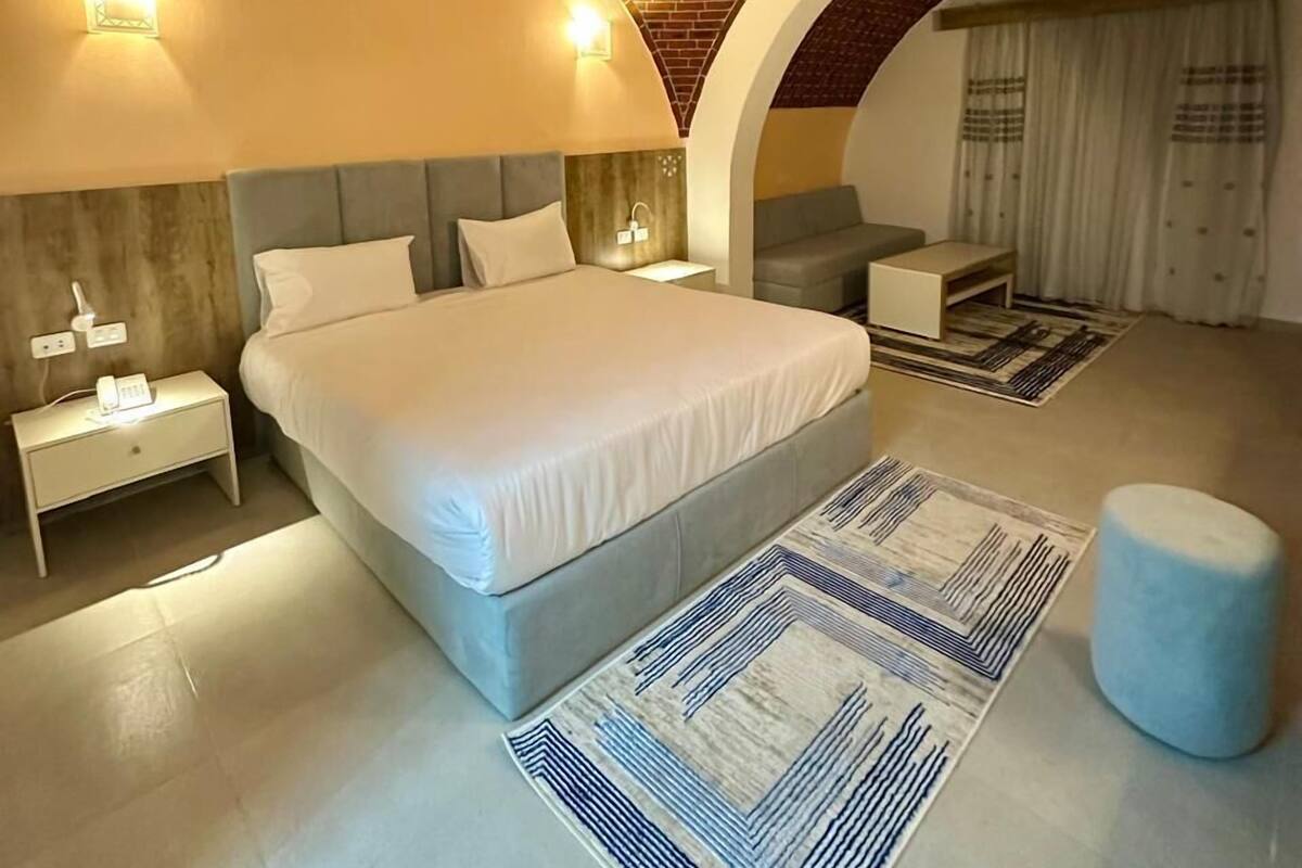 Ein modernes Schlafzimmer mit Ziegeldecke, einem großen Bett, einem Nachttisch, einem Schreibtisch und einem Sessel.