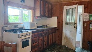Una cocina con armarios de madera, estufa, horno microondas y ventilador de techo.