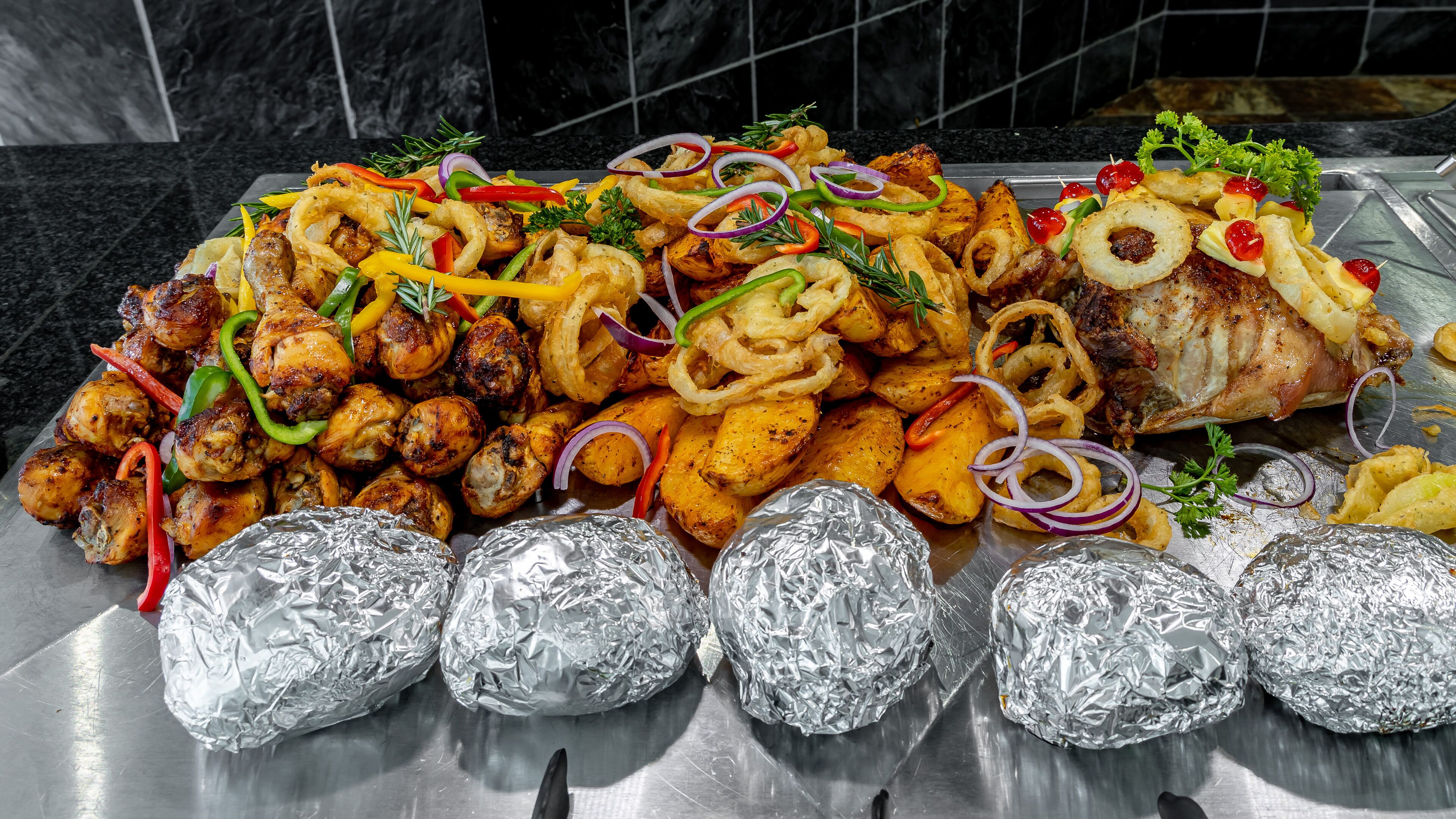 A buffet table with various grilled meats, vegetables, and garnishes.