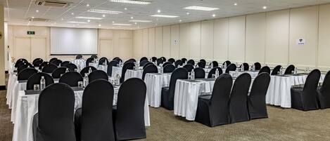 A conference room with rows of tables and chairs, equipped with water bottles and nameplates.