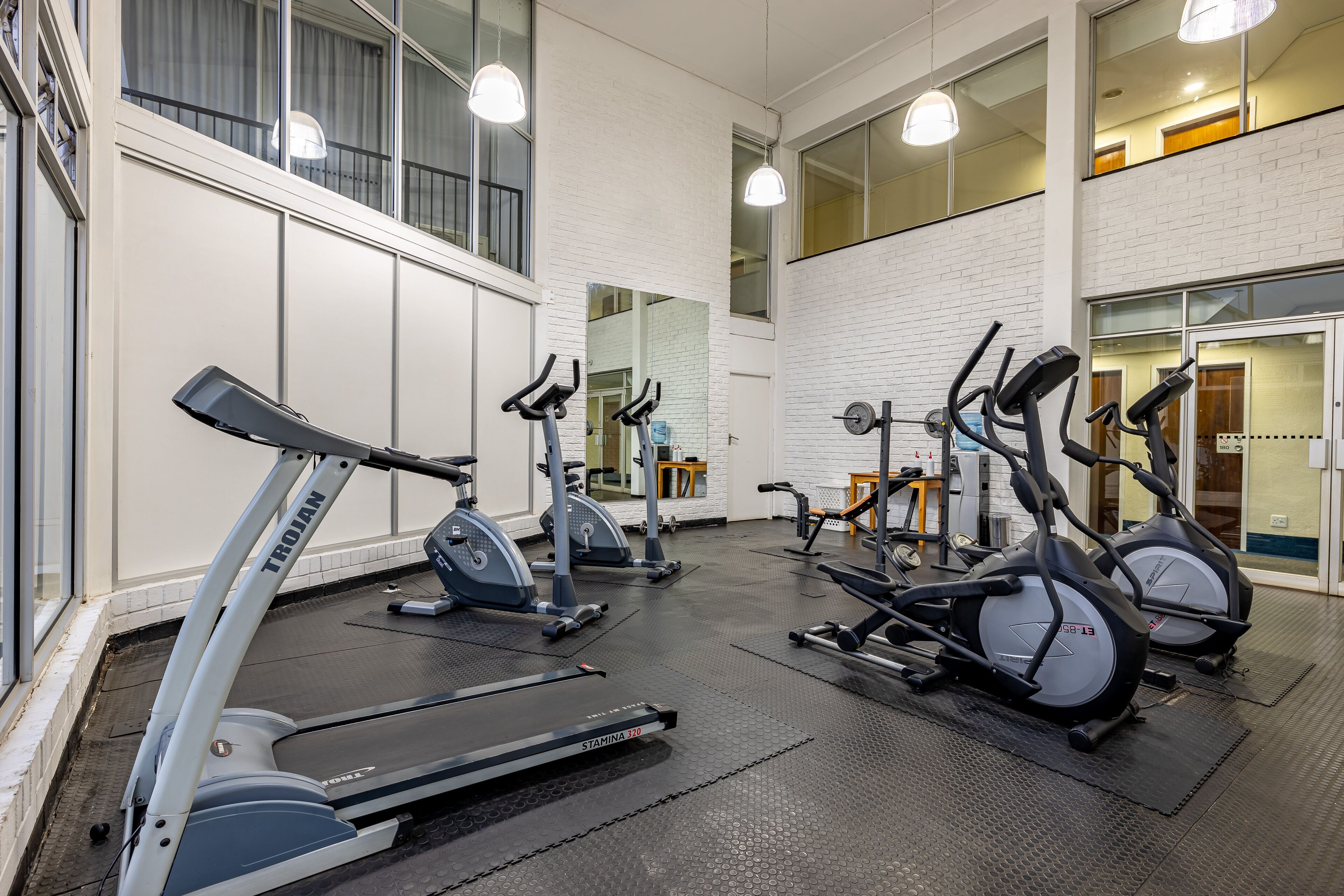 Une salle de sport équipée de tapis de course, de vélos elliptiques et de matériel de musculation.