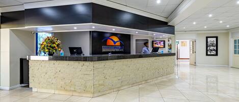 A reception desk with a logo for AfricaSky Hotels and Resorts, a computer, and a vase of flowers.