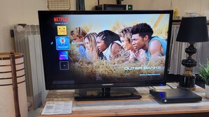 Un téléviseur posé sur un meuble en bois, avec l’interface Netflix visible à l’écran.