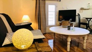 Un salon avec un canapé, une lampe, une table ronde et un téléviseur.