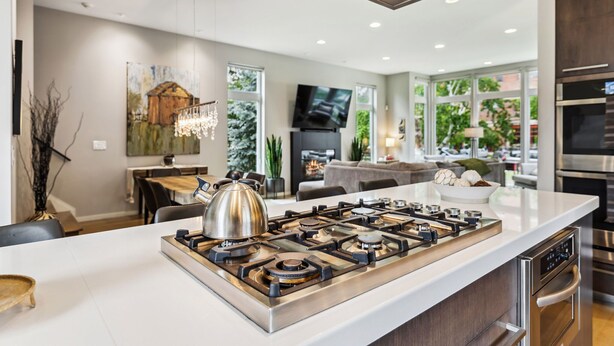 A modern kitchen with a central island, stainless steel appliances, and a large window providing natural light.