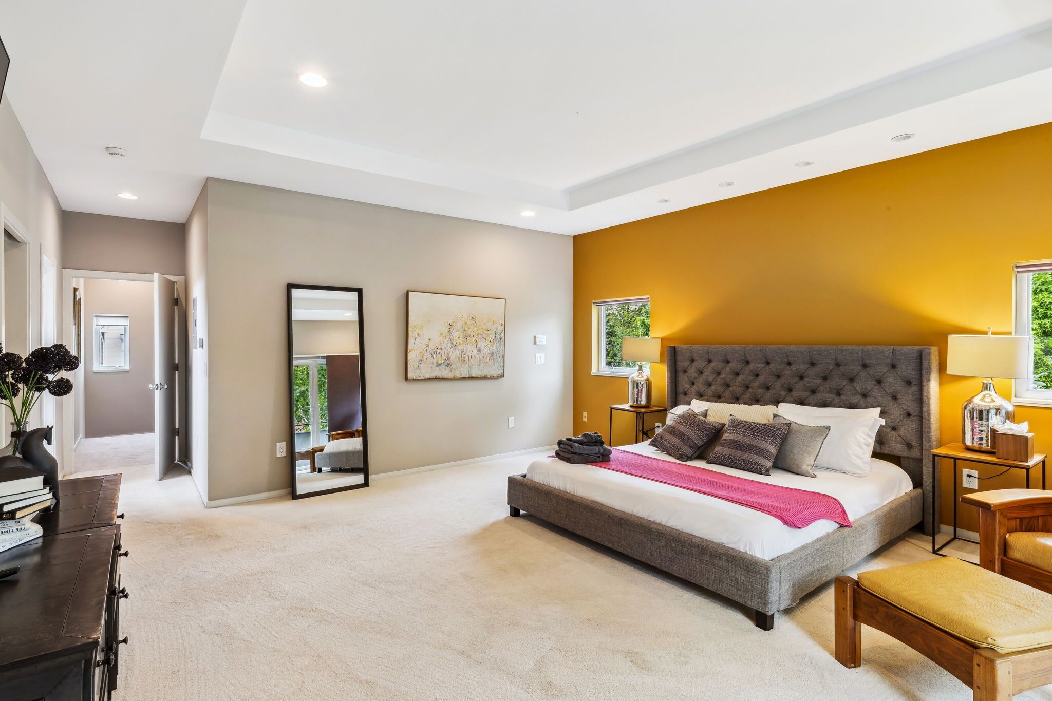 A modern bedroom with a large bed, a bedside table, a nightstand, and a mirror.