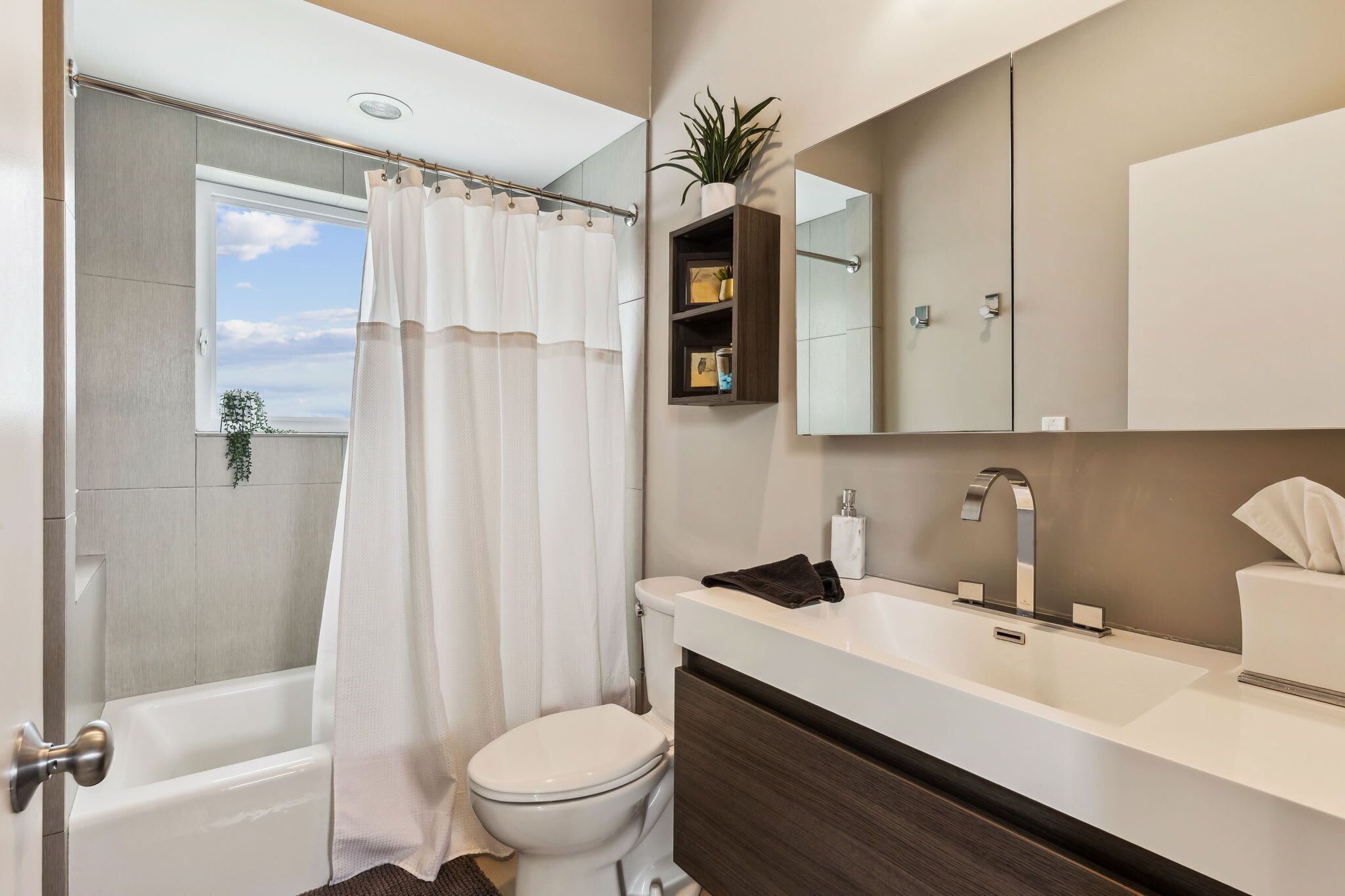 Ein modernes Badezimmer mit Badewanne, Toilette und Waschbecken mit Spiegel darüber.