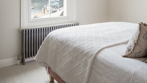 Una camera da letto con un letto, una finestra vista sul porto, un termosifone e una lampada a sospensione.