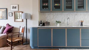 Una cucina moderna con mobili blu, un piano di lavoro in marmo e un lavello incassato.