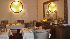 A dining area with round tables, chairs, and a decorative lamp. - Riad Luxe Location LE Grizzly - Chambre LA Kasbah (Marrakech)