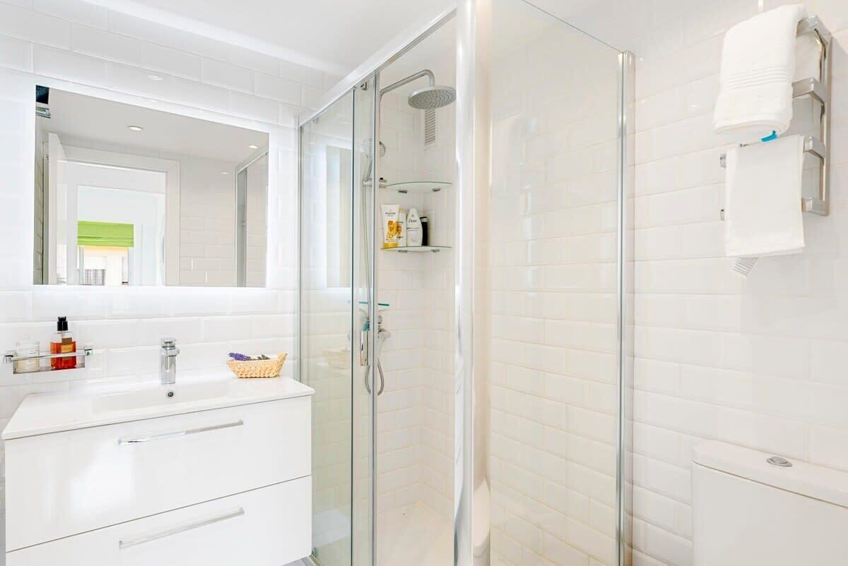 A modern bathroom with a glass-enclosed shower, a white vanity with a mirror, and a toilet.