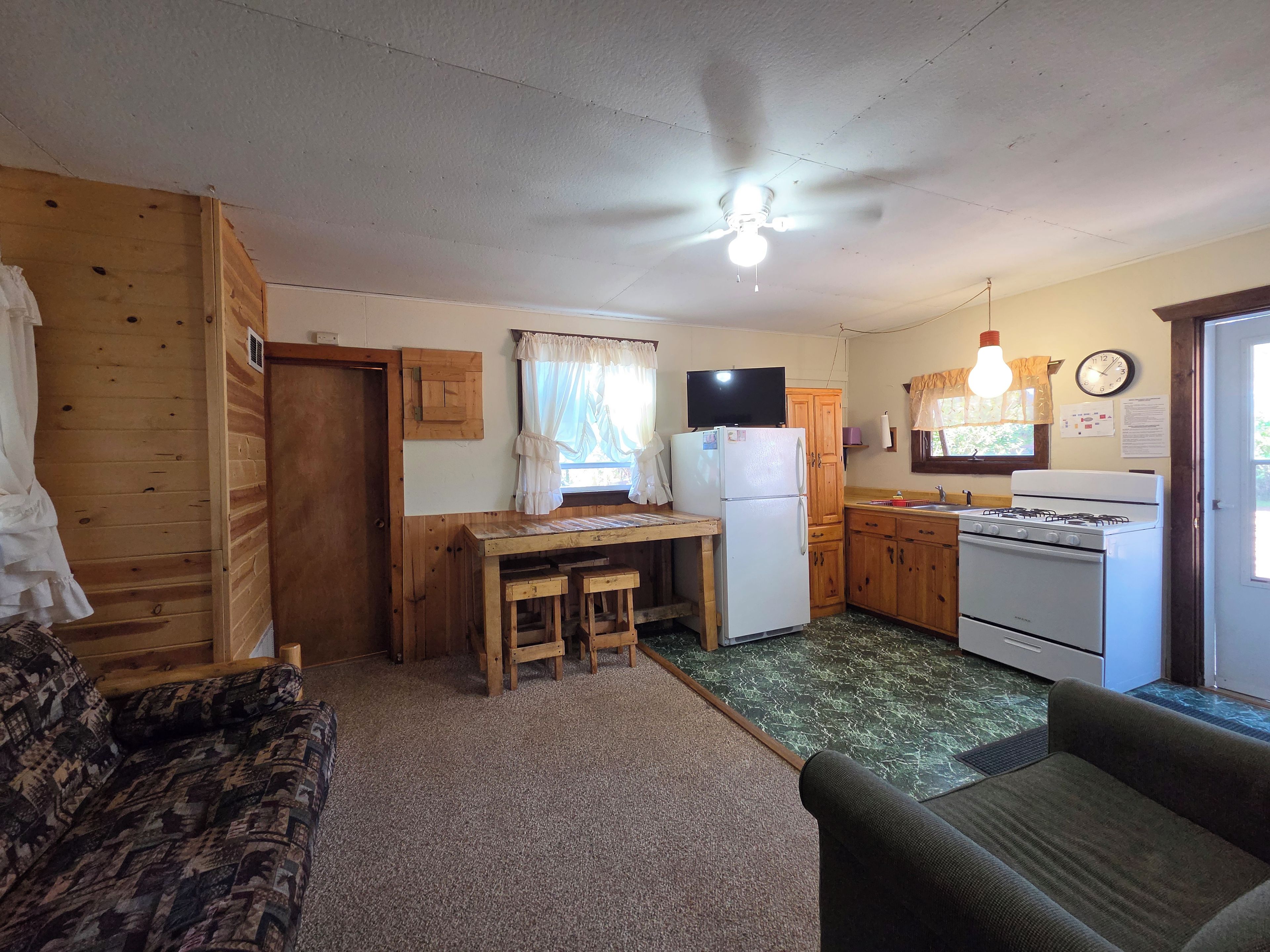 A compact kitchen with a refrigerator, stove, and wooden cabinets.