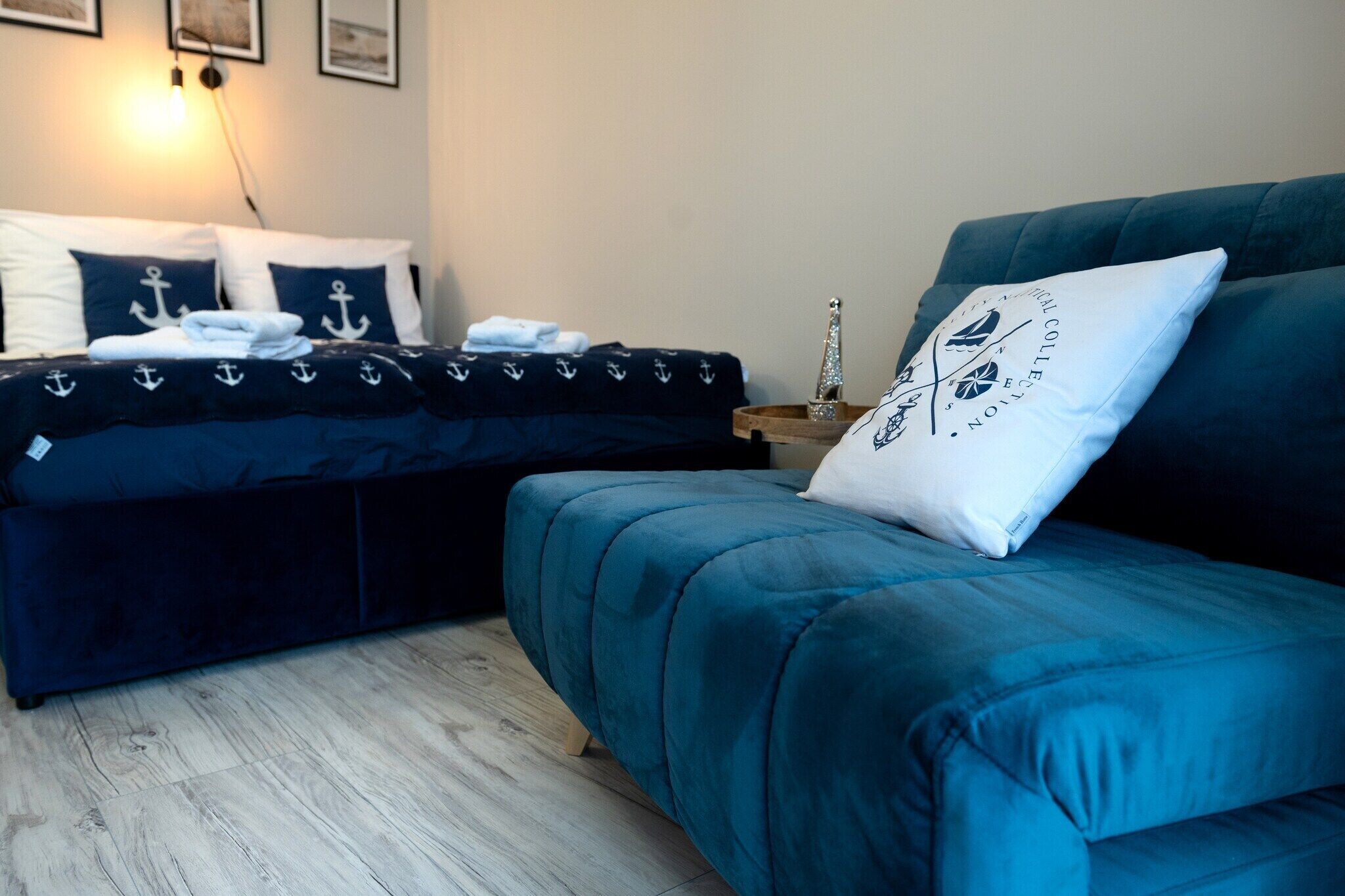 Une chambre à coucher avec un lit, un canapé bleu et une table de chevet avec une lampe.