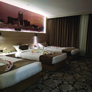 A hotel room with two beds, a large cityscape painting on the wall, and a view of the city.