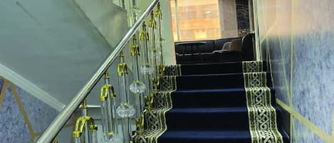Eine Treppe mit aufwendiger Metallgeländerung und gemustertem Teppich.
