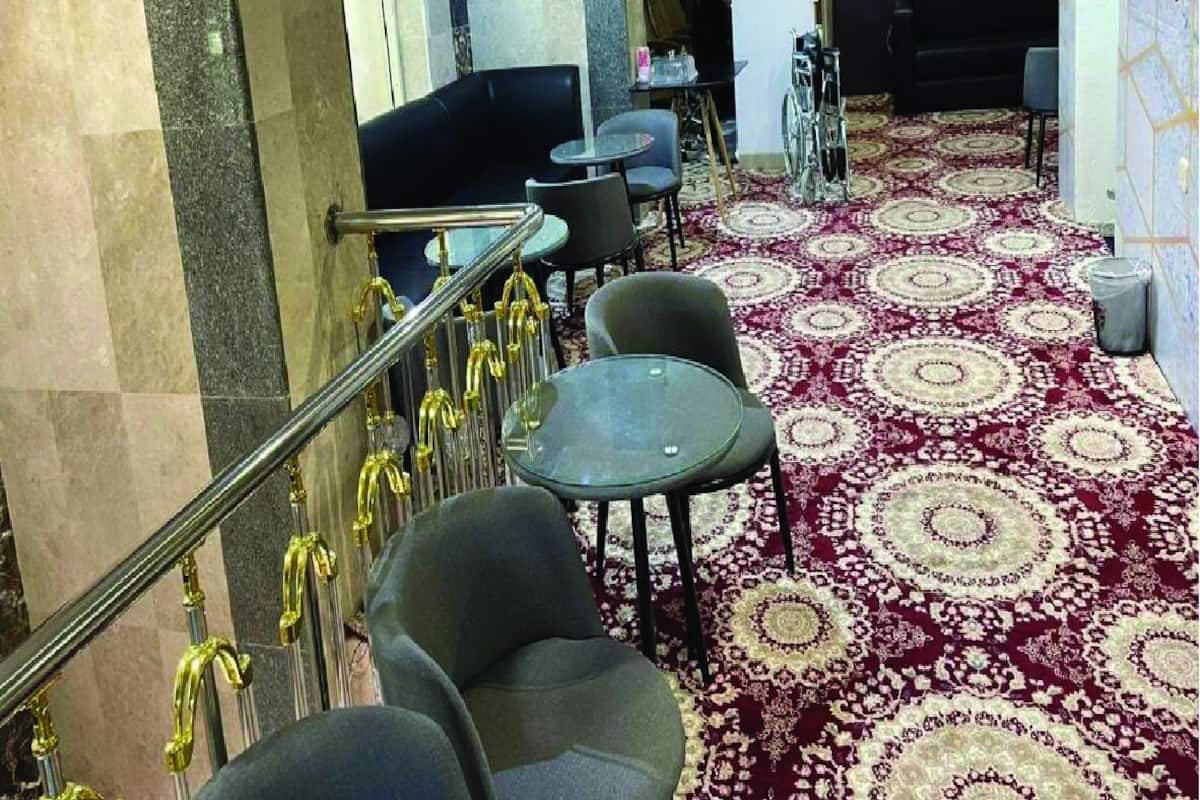 A hotel lobby with a marble staircase, a black sofa, and a patterned carpet.