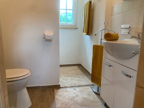 A bathroom with a toilet, sink, and a window providing natural light. - Preber House in Krakaudorf (Krakaudorf)