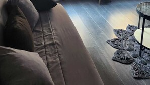 Een moderne woonkamer met een bank, een televisie en uitzicht door grote ramen met luxaflex.