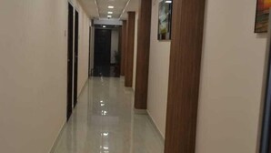 A long, narrow hallway with a shiny floor, wooden columns, and recessed lighting. - AABIL PALACE BUSINESS HOTEL (Chennai)