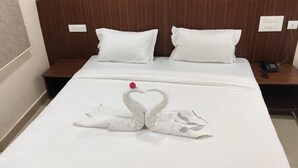 A hotel room with a neatly made bed, a wooden headboard, and a bedside table with a phone. - AABIL PALACE BUSINESS HOTEL (Chennai)