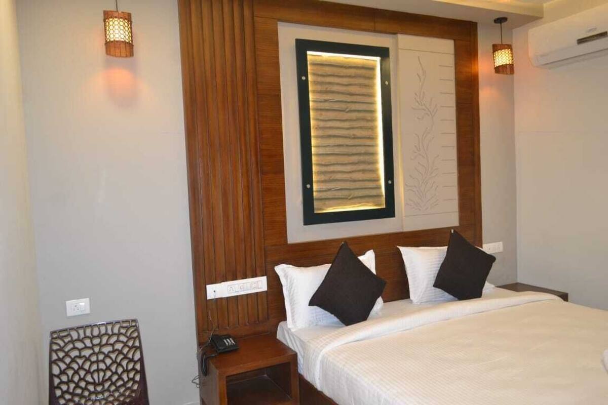 Habitación de hotel con cama, mesita de noche, lámpara de pared y un panel decorativo.