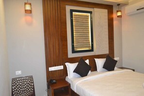 A hotel room with a bed, a nightstand, a wall-mounted lamp, and a decorative panel. - AABIL PALACE BUSINESS HOTEL (Chennai)