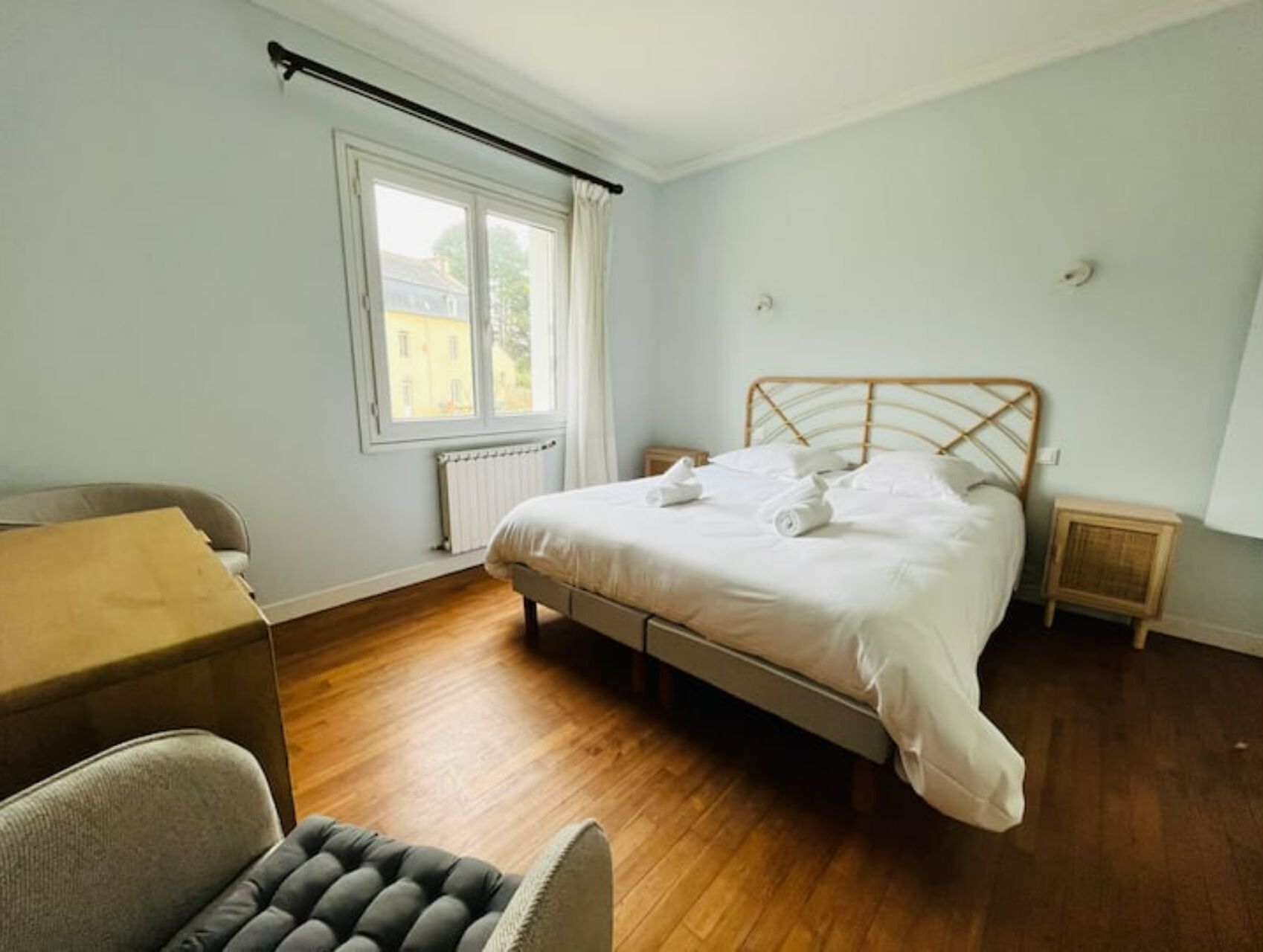 A bedroom with a bed, a chair, a window, and a radiator.