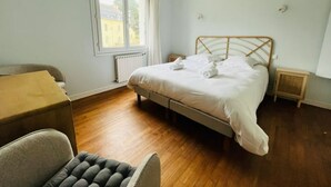 Un dormitorio con cama, una silla, un ventanal y un radiador.