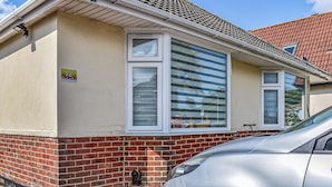 A single-story house with a brick foundation, a tiled roof, and a car parked in front. - 3 bedroom accommodation in Poole (Poole)