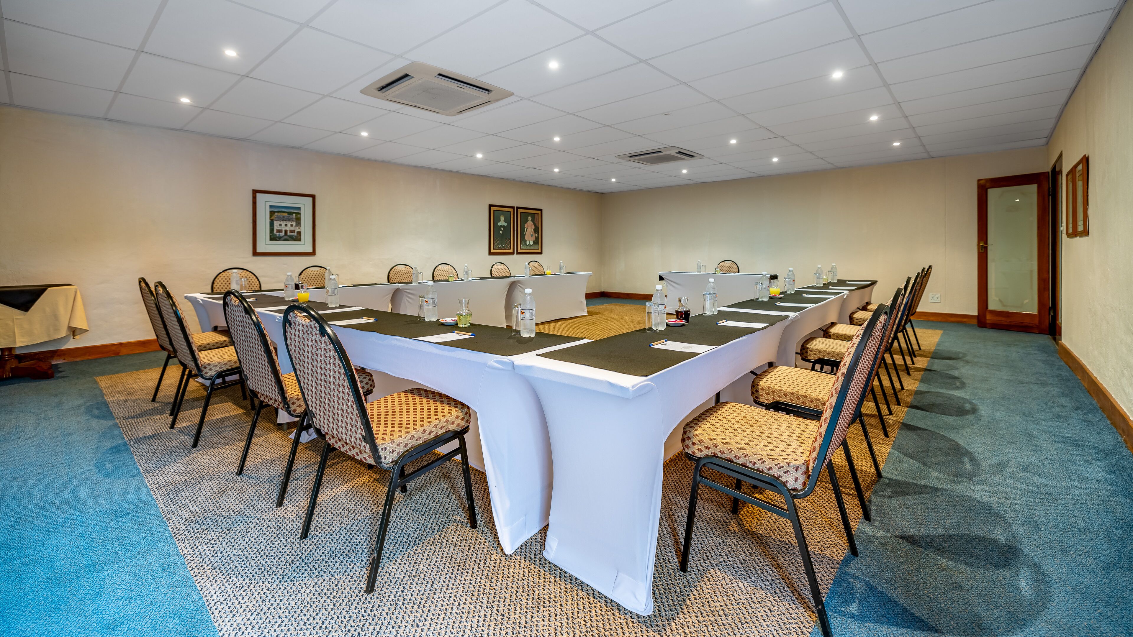 Une salle de conférence avec une longue table, des chaises et un sol recouvert de moquette.