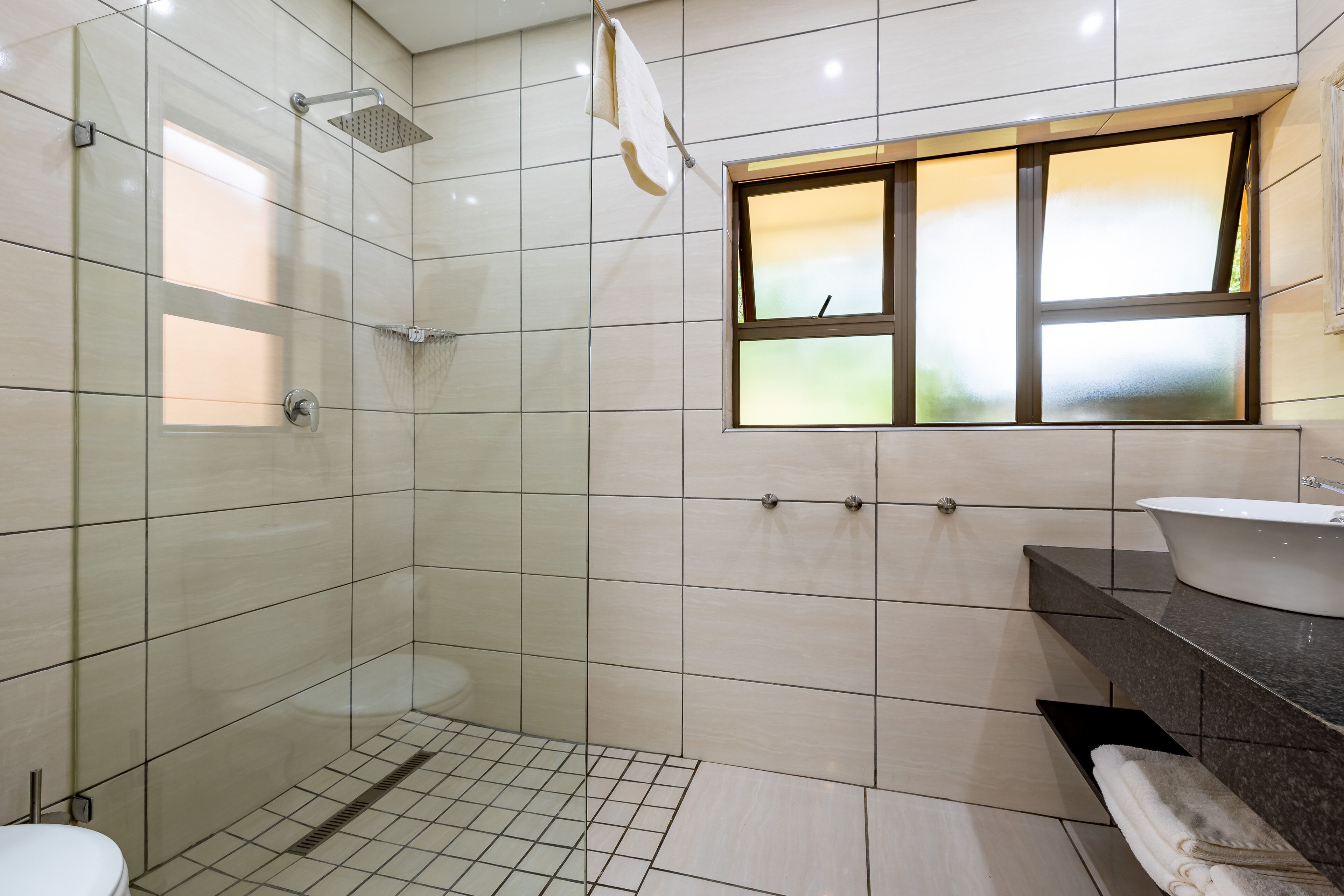 Ein modernes Badezimmer mit einer gläsernen Duschkabine, einer Toilette und einem Waschbecken mit Waschtisch.