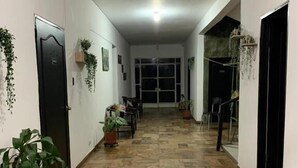Un pasillo con suelo estampado, plantas en macetas y una puerta a la izquierda.