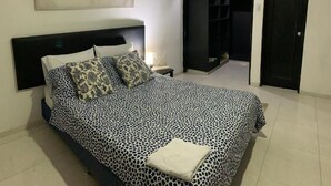 Un dormitorio con una cama, una mesita de noche, un cuadro, un armario y una puerta.