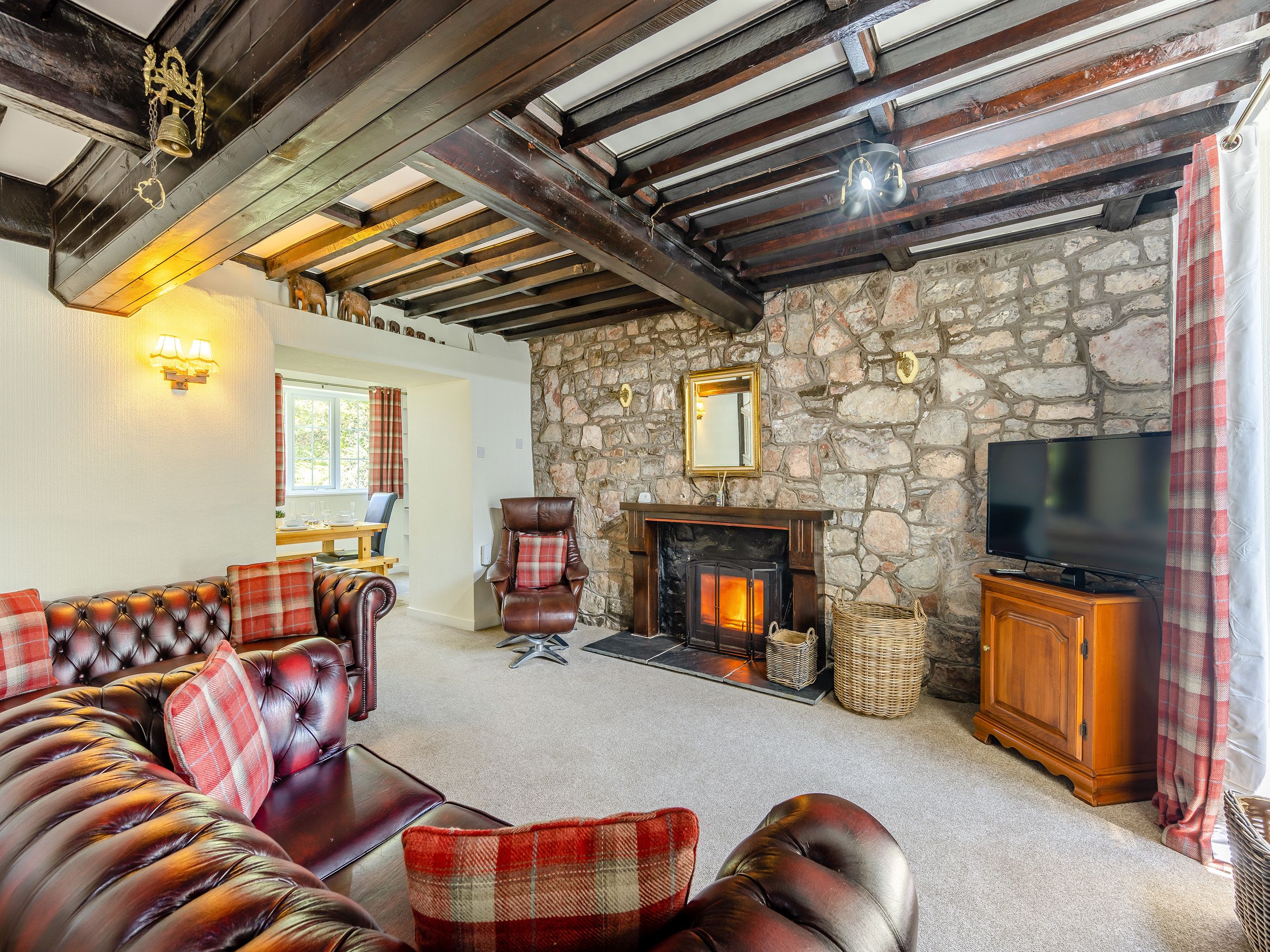 A cozy living room with a stone wall, a fireplace, a leather sofa, and a television.