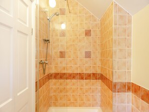 Ein Badezimmer mit Dusche, gefliesten Wänden und einer Badewanne.