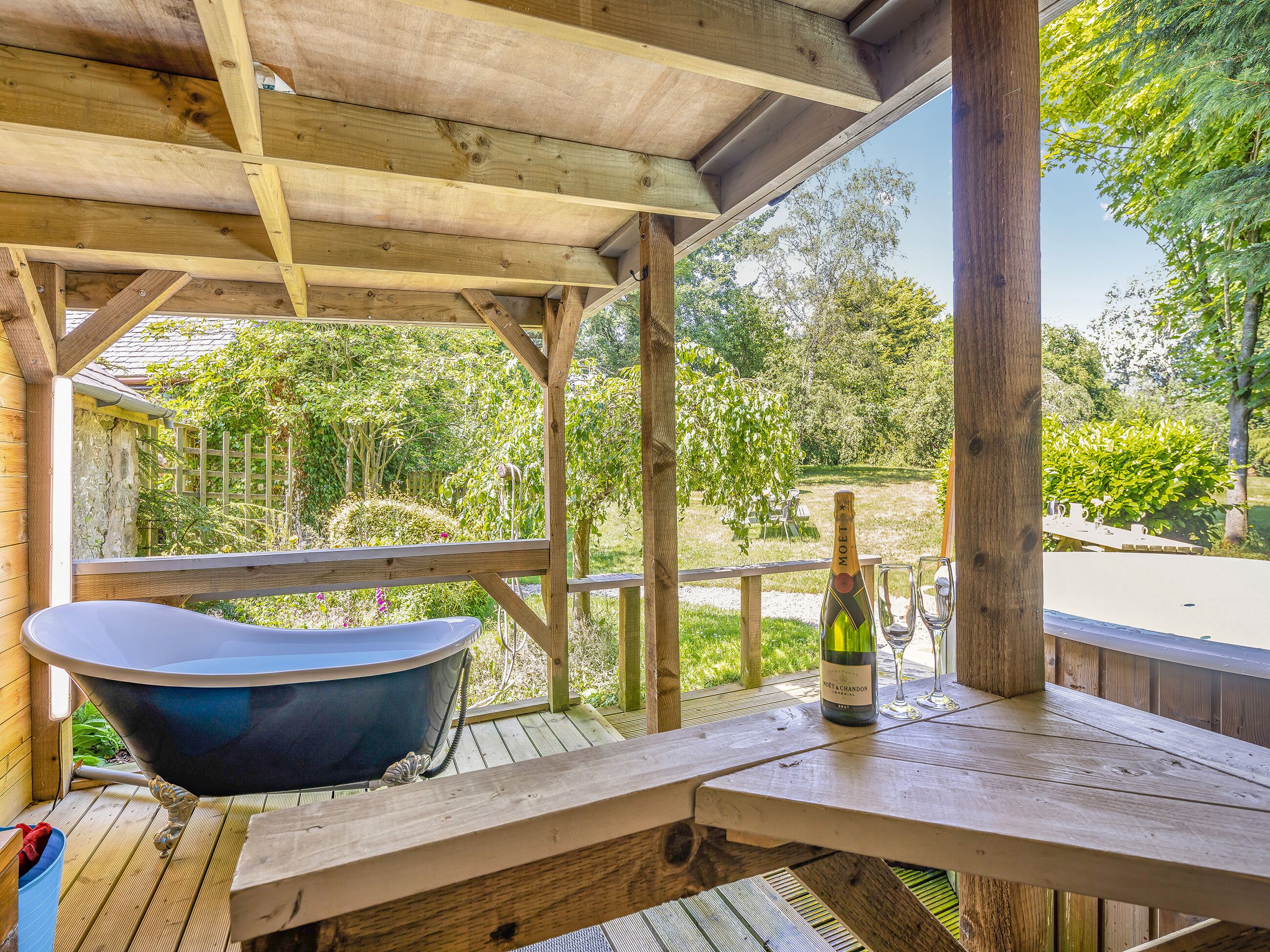 A wooden deck with a hot tub, a bottle of wine, and a picnic table.