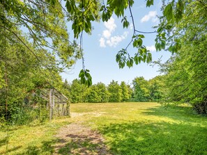 A grassy field with a wooden structure and dense trees. - The Farmhouse - UKC6678 (Betws Yn Rhos)